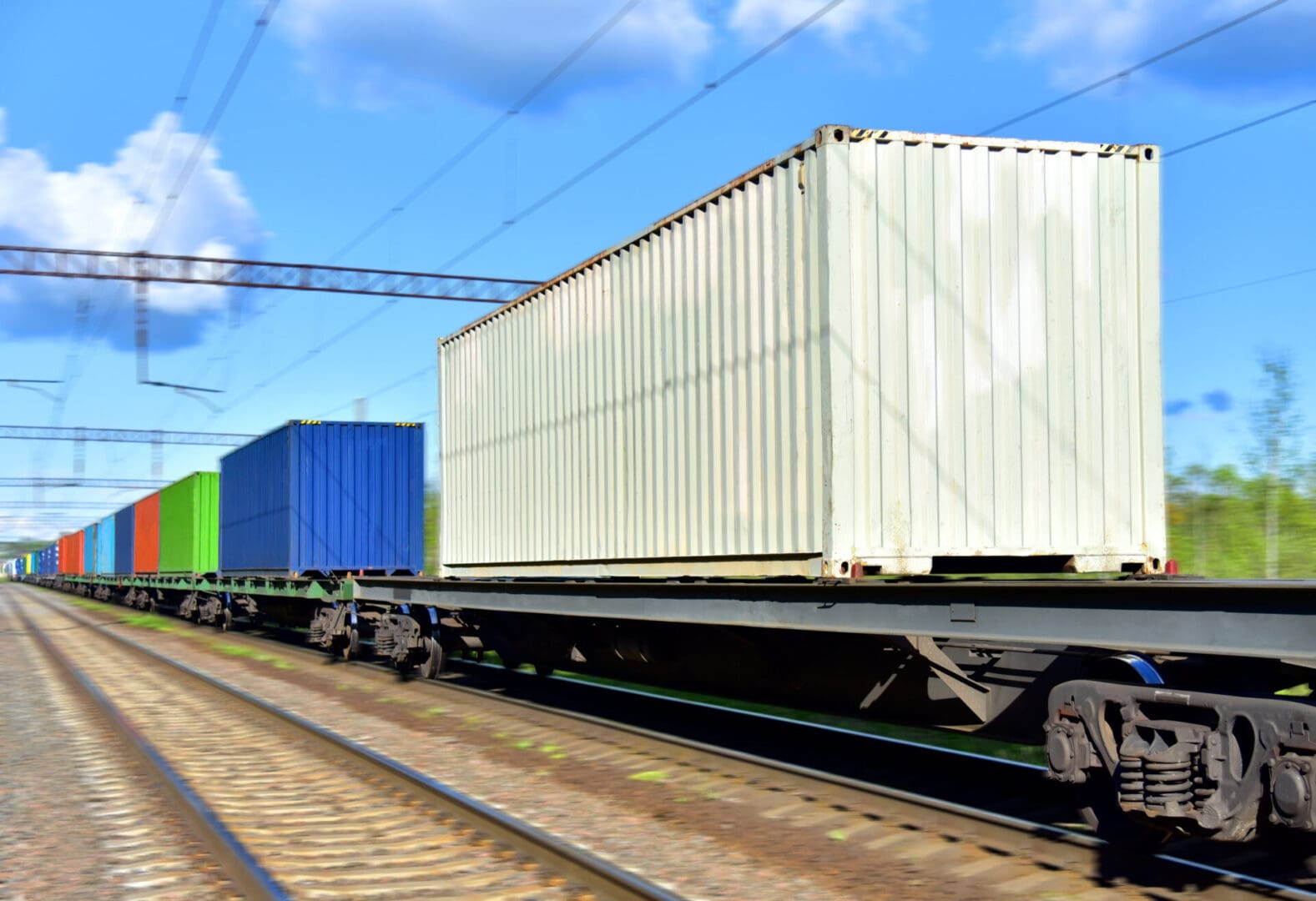 White container leading multicolored train cars
