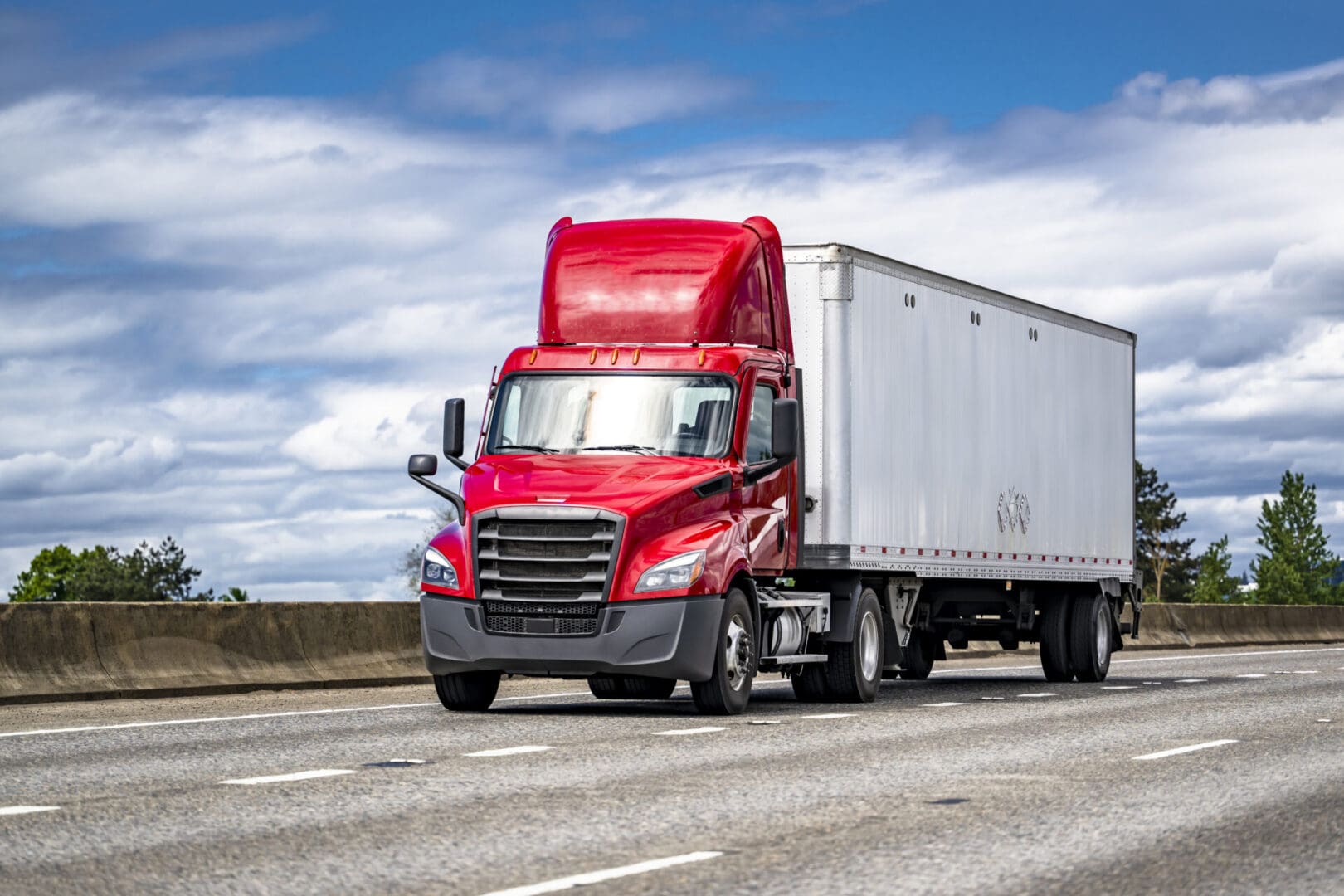 Red semi-truck driving on a highway.