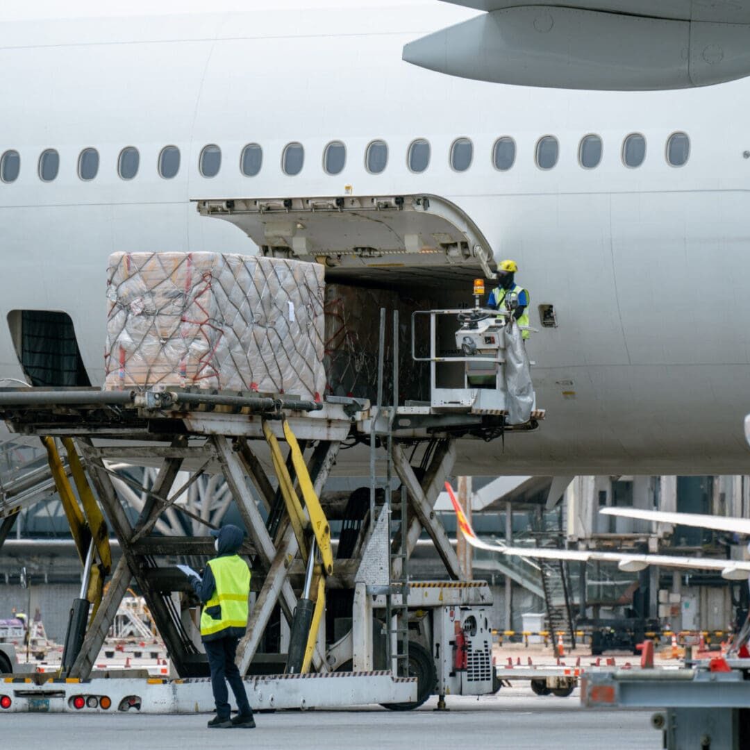 Workers are loading cargo logistic containers to an airplane. Loading cargo onto a large aircraft.